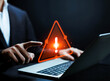 © buraporn - Cyber security warning concept, businessman pointing at laptop with glowing red alert icon, data breach notification, online threat detection, information protection and corporate risk management str