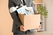 © Pixel-Shot - Fired young man holding box of personal stuff in office, closeup