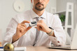 © Pixel-Shot - Young businessman with pulse oximeter at table in office, closeup