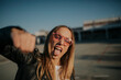 © Westend61 - Portrait of young woman outdoors sticking out tongue and punching