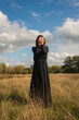 © Milou Dirks - art portrait of woman in black classic dress in field veiled in autumn light
