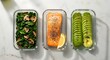 © Designer - Three glass meal prep containers hold healthy portions of salmon, spinach, and sliced avocado on a light surface.