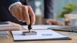 © Opaopi - Person stamping document with official seal at desk close up for business concept