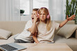 © SHOTPRIME STUDIO - Two children sitting on a couch with one girl wearing pink headphones showing a displeased expression while the boy next to her shouts. Concept of sibling interaction and playful annoyance.