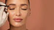 © Home-stock - Hand holding tweezers and shaping eyebrows to young European woman, beautician plucking brow hairs of lady over pink background, closeup
