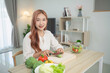 © WMSTUDIO - Young woman happily preparing fresh vegetables in a bright kitchen, showcasing her culinary skills and healthy lifestyle with vibrant ingredients