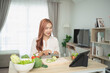 © WMSTUDIO - Young woman preparing healthy salad in kitchen, chopping fresh vegetables while following recipe on tablet, promoting cooking at home, lifestyle and wellness