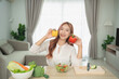 © WMSTUDIO - Cheerful young woman holding yellow and red bell peppers in a kitchen, preparing fresh salad with colorful vegetables and a bright atmosphere