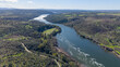 © AmazingAerialAgency - Aerial view of the serene Tagus River winding through a landscape of verdant trees, creating a beautiful contrast between the dark waters and the bright foliage, Caceres, Caceres, Espana.