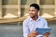 © Lumos sp - Portrait of a young  businessman wman using a tablet computer  in a city park, surrounded by modern corporate office buildings architecture