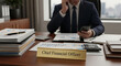 © MUHAMMAD - Chief Financial Officer reviewing financial reports on mobile device at office desk with documents and calculator