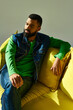 © LIGHTFIELD STUDIOS - Young man exudes style and confidence while relaxing on a vibrant yellow sofa