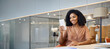 © insta_photos - Young happy African American business woman using mobile phone sitting in corporate office. Professional female execuitve or entrepreneur looking at smartphone working with cellphone in hands.