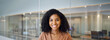 © insta_photos - Happy confident young African American business woman, entrepreneur or employee standing in office. Smiling professional businesswoman with curly hair looking at camera at work, headshot portrait.