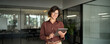 © insta_photos - Happy businesswoman company manager, female entrepreneur or employee looking at camera. Smiling young Hispanic professional business woman wearing glasses using tablet standing in office. Portrait