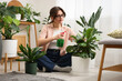 © New Africa - Woman spraying beautiful potted houseplant with water indoors