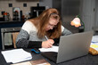 © Мар'ян Філь - A middle-aged woman concentrates on paperwork while using a laptop at a kitchen workspace. A woman works from home and raises children at same time