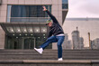 © Nano - A young adult dances hip hop breakdance, jumping and dancing enthusiastically in the streets. He wears comfortable clothes and exudes attitude, movement, and positive energy. Street dance, freestyle
