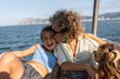 © Alvaro Lavin/Stocksy - Happy family enjoying boat trip on sea with mother kissing daughter