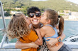 © Alvaro Lavin/Stocksy - Happy family kissing mother on boat trip vacation
