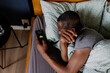 © Oleksii Syrotkin/Stocksy - Top view of adult black man turning off alarm on smartphone in bed