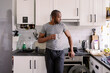 © Oleksii Syrotkin/Stocksy - Thoughtful man standing and drinking water from glass on kitchen