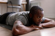 © Oleksii Syrotkin/Stocksy - Thoughtful adult black man lying and resting on fitness mat at home