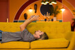 © Dmitry Homich/Stocksy - a guy lounging on the couch looking at his phone.