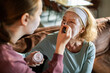 © Geber86 - Teenage girl applying face mask to senior woman at home