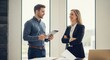 © Von - Two business professionals discussing a project in a modern office setting.