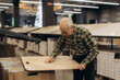 © Roman - Senior man choosing wood flooring in hardware store