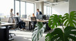 © Sanoor - Office workers collaborating in modern workspace with green plant natural light and blurred background