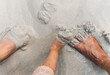 © explorewithinfo - child and parent playing with wet sand beside bare feet on beach