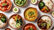 © thenort - Overhead view showcasing assorted Indian curries and rice in terracotta bowls on white surface