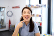 © littlewolf1989 - Speech pathologist showing open mouth and demonstrating articulation exercise, pointing to chin while performing a tongue movement for therapy in a clinic setting