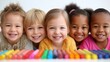 © Nick Freund - Fünf lächelnde Kinder unterschiedlicher Herkunft liegen nebeneinander hinter bunten Buntstiften