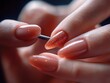 © zhuan - close-up of well-manicured hands with glossy peach gel nails and a glitter accent nail being worked on with a metal tool, conveying delicate pampering and precise beauty care