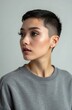 © Pete - Young woman with short dark hair and stylish makeup poses indoors. She wears a grey sweatshirt. Vertical studio shot emphasizes her face and shoulders. She looks aside with a calm expression.