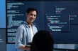 © SAT65 - Male software engineer presenting a Coding Task, AI chatbot workflow with code on multiple monitors in a modern office. coding collaboration and agile projects Concept.