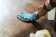 © Bratislav - Person cleans wooden floor with cloth and spray bottle in home setting during day