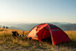 © marina_larina - Cozy campsite mountain meadow golden hour. Red tourist tent pitched field. Small table with espresso maker metal mugs. Beautiful landscape vista. Peaceful trekking vacation adventure nomadic life