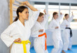 © JackF - In gym, certified woman master coach conducts karate kata lesson with young female students group and shows sequence of actions when conducting close fight