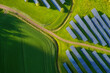 © Pavel Babic - Aerial view of a vast solar panel farm nestled within lush green agricultural fields