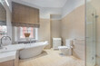 © Alhim - A bright bathroom features a separate glass shower, a spacious bathtub, and a toilet. Natural light comes through the window, illuminating the clean design and neutral colors