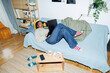 © Jimena Roquero/Stocksy - Woman at home chilling on couch using laptop.. Direct flash