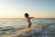 © Stephanie Tamir/Stocksy - A little toddler smiling and jumping in the water at sunset.