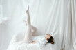 © Tania Cervian/Stocksy - Woman laying down in white against soft backdrop