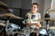 © Maria Sher/Stocksy - Smiling boy playing drum in recording studio