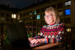 © Ibai Acevedo/Stocksy - Senior woman using laptop on home terrace at night