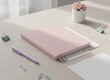 © mohdfaizal - Pink closed notebook with pen and plant on desk